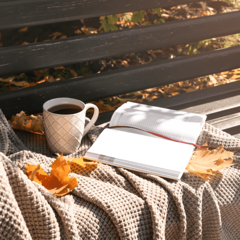 Herbststimmung mit heißem Getränk, Decke und Buch 